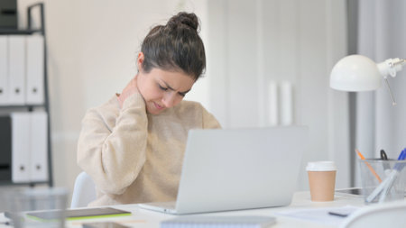 Young Indian Woman with Laptop having Neck Painの写真素材