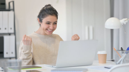 Young Indian Woman with Laptop Celebrating Successの写真素材