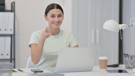 Young Latin Woman with Laptop Pointing at the Cameraの写真素材