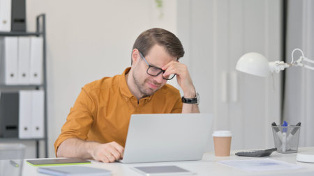 Young Man having Loss on Laptop in Officeの写真素材