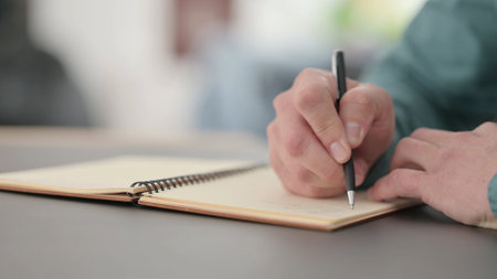 Close up of Hands of Man Writing in Notebook