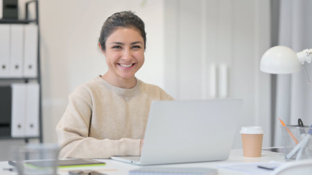 Young Indian Woman with Laptop Smiling at Cameraの写真素材