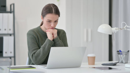 Pensive young Woman Working on Laptopの写真素材