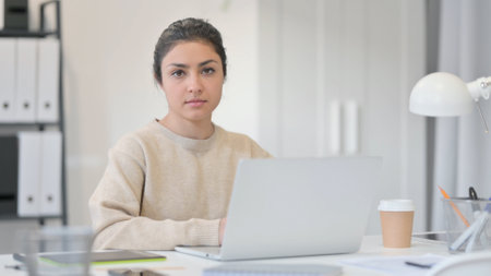 Young Indian Woman with Laptop Looking at Cameraの写真素材