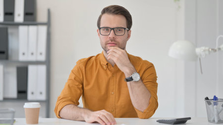 Thinking Young Man Sitting in Officeの写真素材