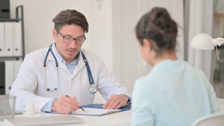 Male Doctor Writing Prescription for Patientの写真素材