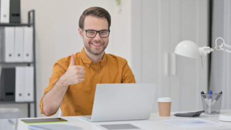 Thumbs Up by Young Man with Laptopの写真素材