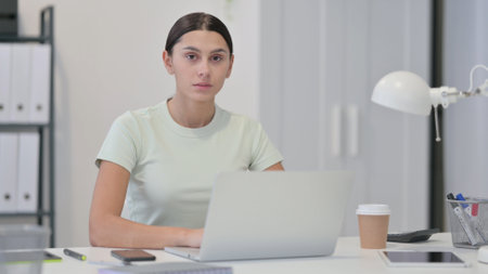 Young Latin Woman with Laptop Looking at Cameraの写真素材