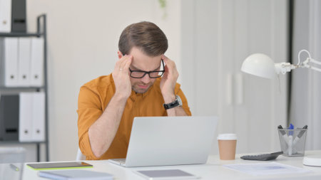 Tense Young Man having Headache at Workの写真素材