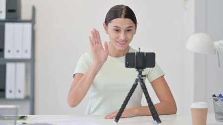 Young Latin Woman Blogging on Smartphone, Waving handの写真素材
