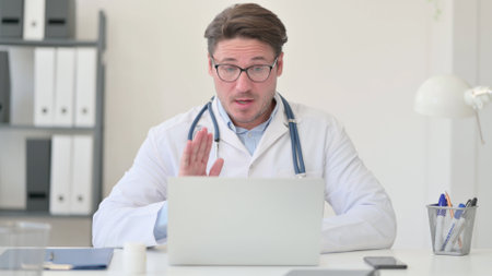 Video Call on Laptop by Middle Aged Male Doctorの写真素材