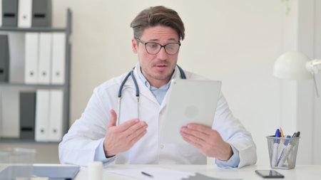 Video Call on Tablet by Middle Aged Male Doctorの写真素材