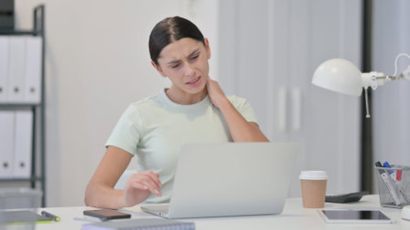 Young Latin Woman with Laptop having Neck Painの写真素材