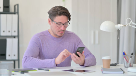 Middle Aged Man using Smartphone in Officeの写真素材
