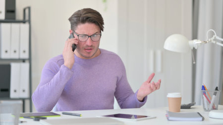Angry Middle Aged Man Talking on Smartphoneの写真素材