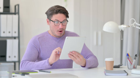Middle Aged Man Shocked by Results on Tabletの写真素材