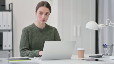 Young Woman with Laptop Looking at Cameraの写真素材