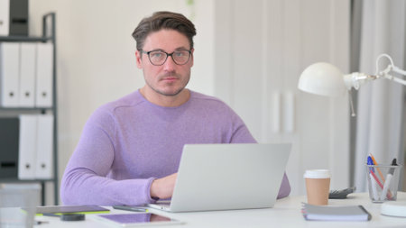 Middle Aged Man with Laptop Looking at the Cameraの写真素材