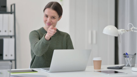 Young Woman with Laptop Pointing at the Cameraの写真素材