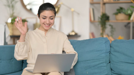 Online Video Call on Laptop by Young Indian Woman on Sofaの写真素材