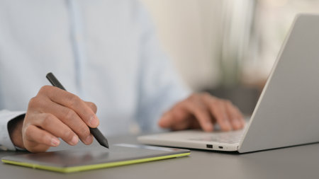 Hands of African Man Designing on Tablet and using Laptopの写真素材