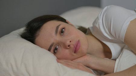 Close up of Young Woman Looking at Camera in Bedの写真素材