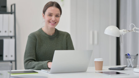 Young Woman with Laptop Smiling at Cameraの写真素材