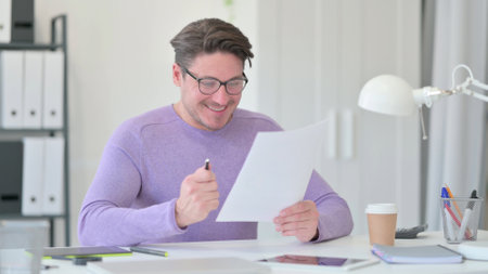 Middle Aged Man with Documents Celebrating Successの写真素材
