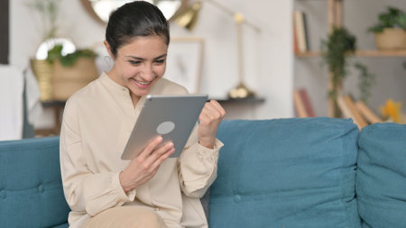 Young Indian Woman Celebrating Win on Tabletの写真素材