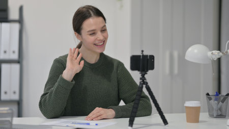 Young Woman Blogging on Smartphone, Waving Handの写真素材