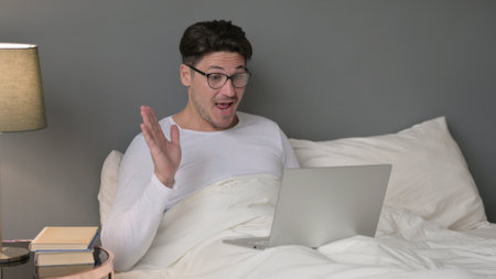 Video Call on Laptop by Middle Aged Man in Bedの写真素材