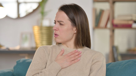 Portrait of Sick Young Woman Coughing at Homeの写真素材