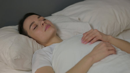 Peaceful Young Woman Sleeping in Bedの写真素材