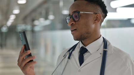 Portrait of Young Male African Doctor doing Video Call on Smartphone