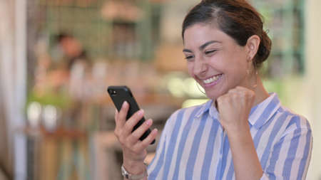 Portrait of Cheerful Indian Woman Celebrating Success on Smartphone