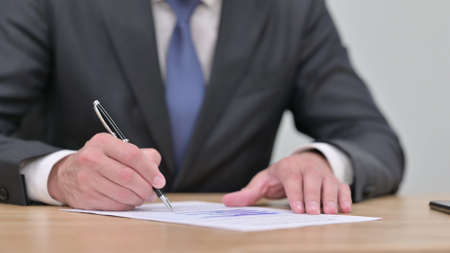 Close up of Hands of Businessman Writing on Paper, Signing Contract