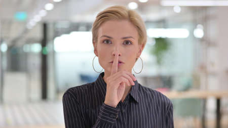 Portrait of Young Businesswoman Putting Finger on Lips, Quiet Signの写真素材