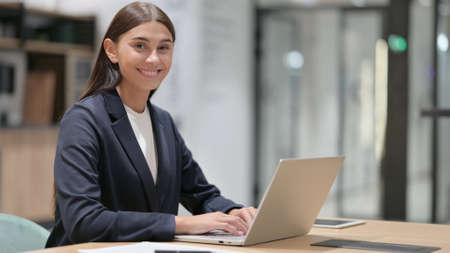 Cheerful Businesswoman with Laptop Smiling at Cameraの写真素材