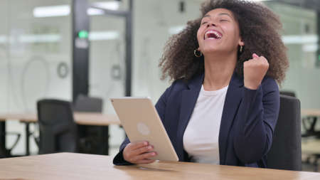 Excited African Businesswoman Celebrating Success on Tablet