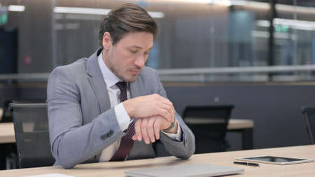 Anxious Businessman Checking Smartwatch while Waitingの写真素材