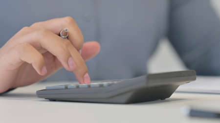 Close Up of African Woman using Calculator, Writing on Paperの写真素材