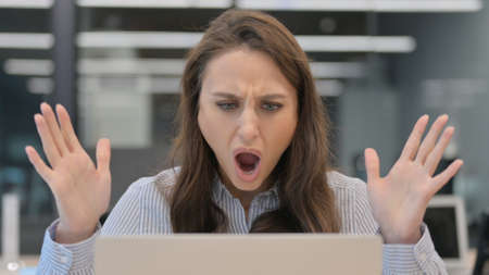 Young Businesswoman Shocked by Results on Laptop