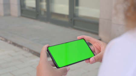 Rear View of African Woman Looking at Smartphone with Green Chroma Screen