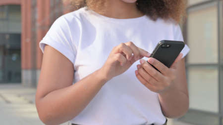 Close up of Walking African Woman Using Smartphone, on Streetの写真素材