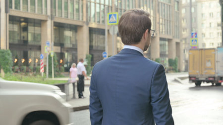 Back View of Young Businessman Walking on Streetの写真素材