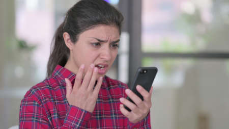 Indian woman Reacting to Loss on Smartphoneの写真素材