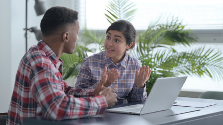 African Man and Indian Woman Arguing while Working on Laptop