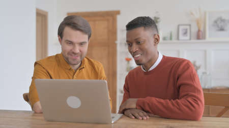 African Man and Young Man Discussing Work on Laptop
