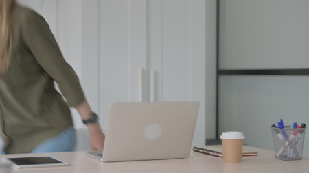 Blonde Young Woman Leaving Office after Closing Laptopの写真素材