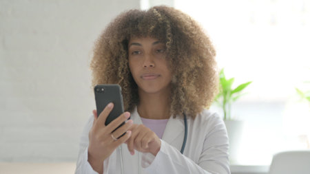 Female African Doctor using Smartphone for Browsing Internetの写真素材